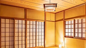 Una habitación japonesa tradicional con suelo de tatami, paneles shoji y una cama de madera baja.