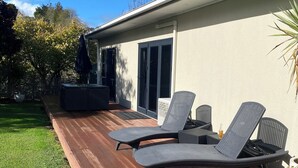 Une terrasse avec des chaises longues, un patio couvert et une maison dotée d’une porte-fenêtre coulissante.