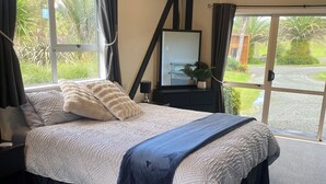 Une chambre avec un grand lit, une commode, un miroir et une vue sur l’extérieur.