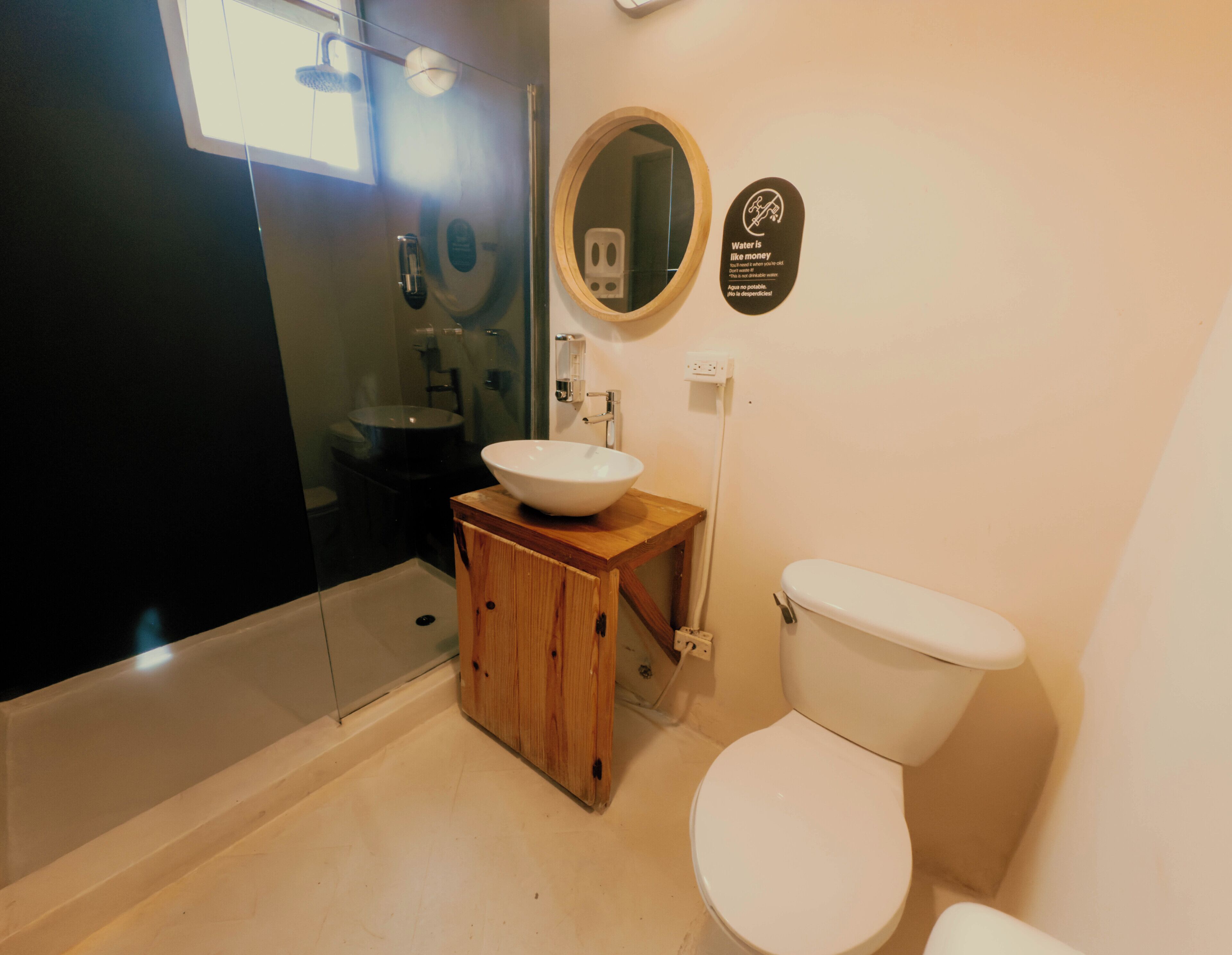 Un baño con tocador de madera, un lavamanos blanco, un inodoro y un espejo.
