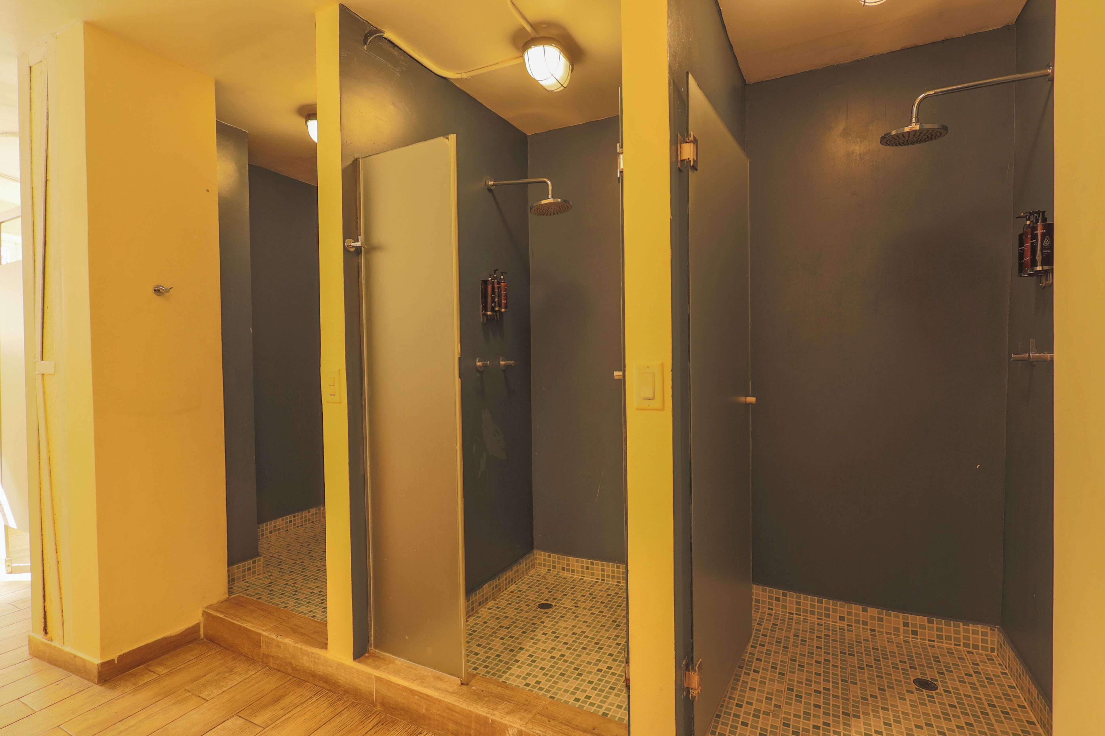 A bathroom with a shower, tiled floor, and a door leading to another room.