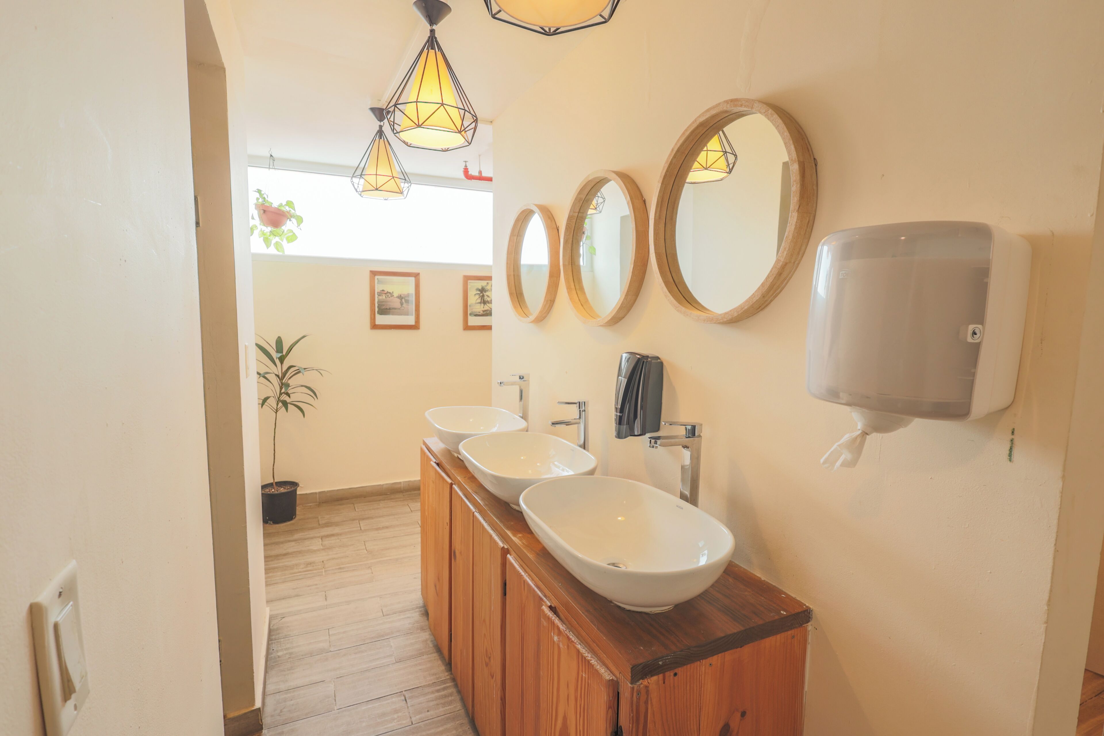 Une salle de bain avec trois lavabos, des meubles en bois et un sèche-mains.