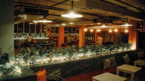 Un restaurant doté d’un long comptoir, de plusieurs tables et d’un aquarium décoratif.