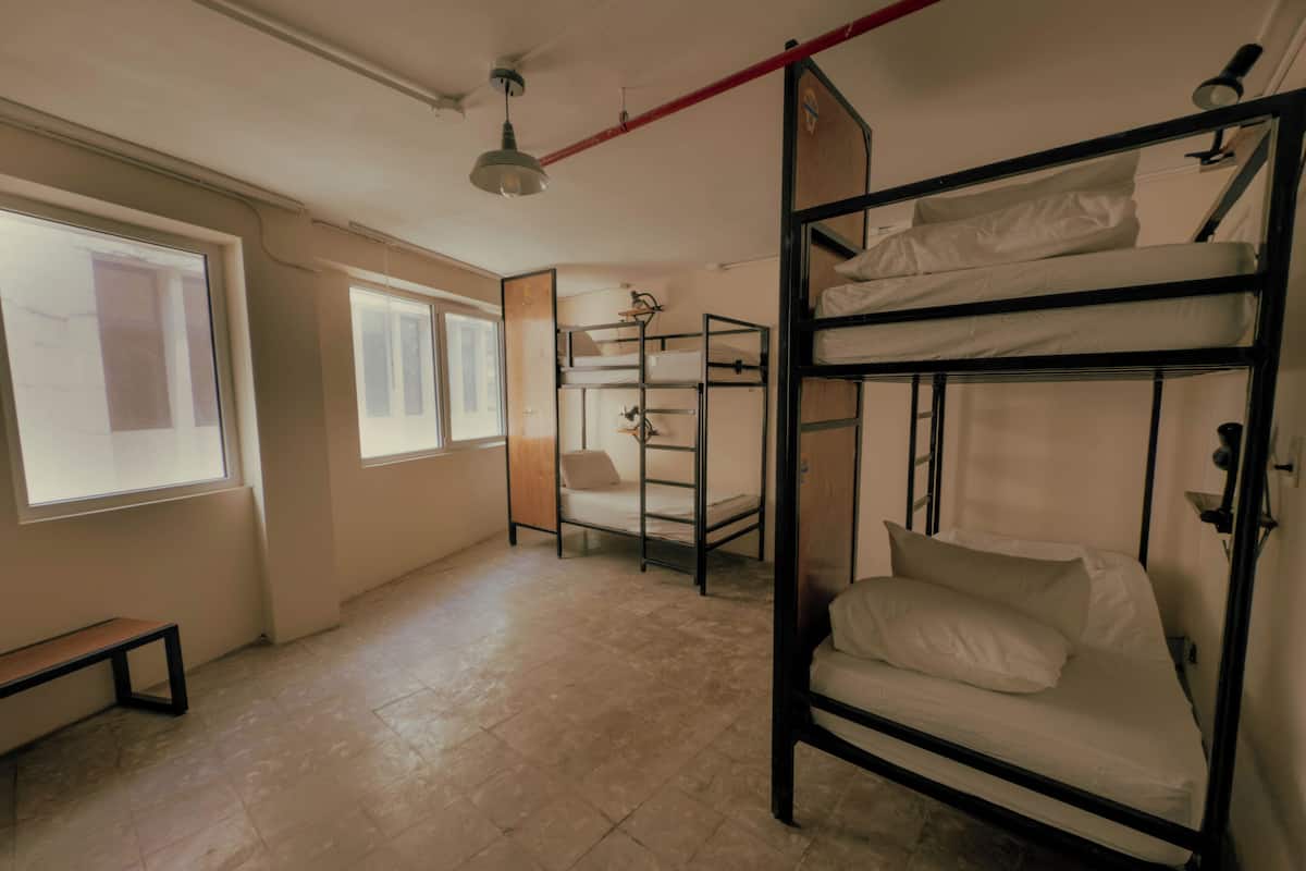 Um quarto de dormitório com beliches, um banco e uma janela que oferece luz natural.