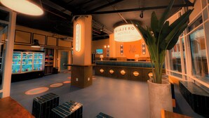 A modern hotel lobby with a reception desk, a large potted plant, and a minibar. - Viajero Casco Viejo Hostel (Panama City)