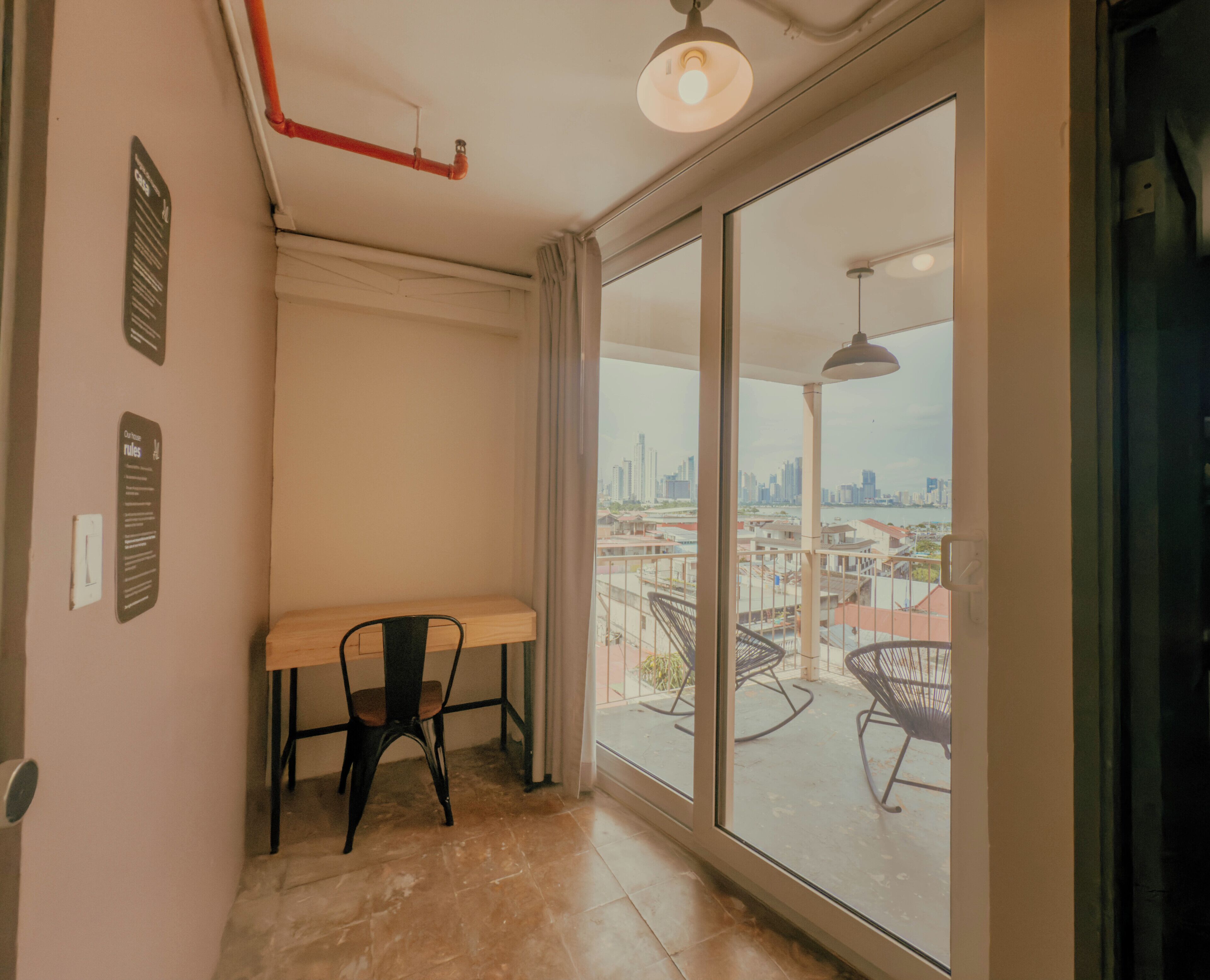 A room with a large sliding glass door leading to a balcony with a city view.