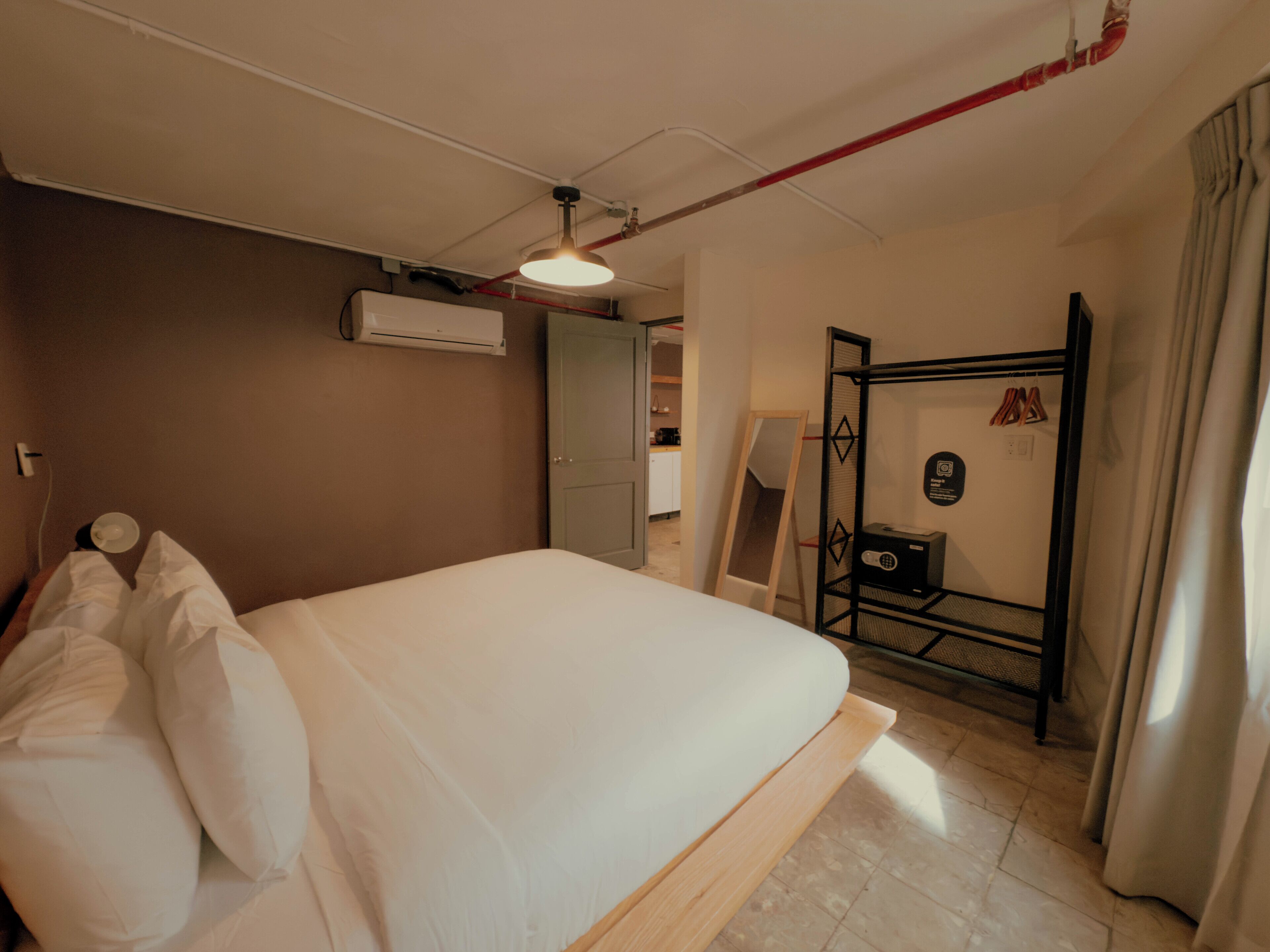 A bedroom with a bed, an air conditioning unit, a mirror, and a wardrobe.