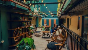 Un café chaleureux, avec des meubles en bois, des plantes en pot et des tuyaux apparents.