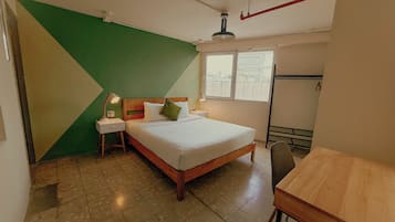 A bedroom with a bed, bedside tables, a window, and a wooden table.