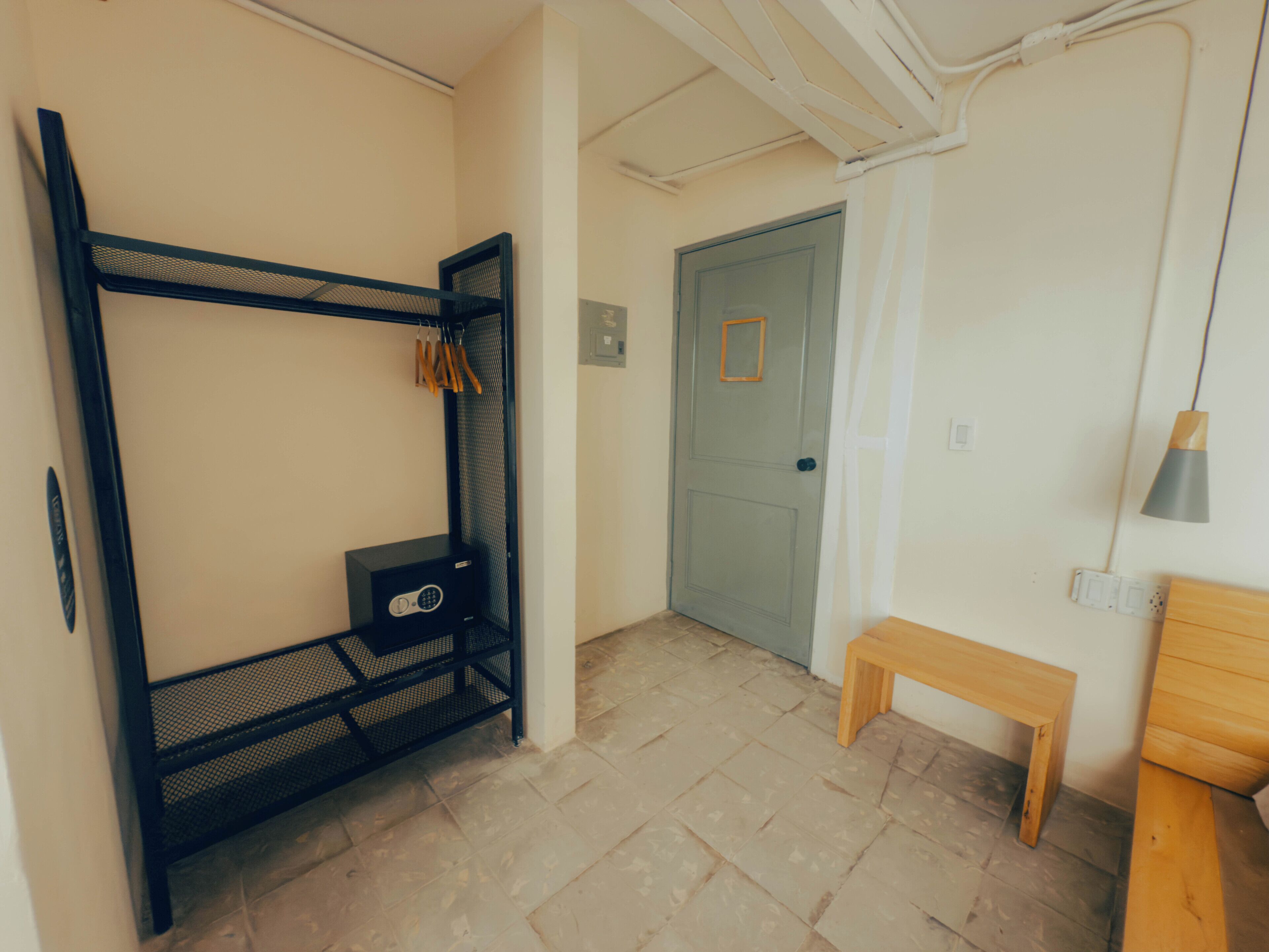 A room with a bunk bed, a small desk, a bench, and a door.