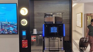 Une machine à café en libre-service dotée d’un écran numérique, d’un terminal de paiement et d’un distributeur de café.