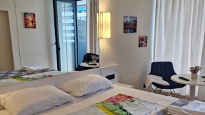 Une chambre d’hôtel avec un grand lit, un bureau, une chaise, un miroir et une fenêtre avec des rideaux.
