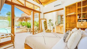Ein Schlafzimmer mit einem großen Bett, Holzmöbeln, Blick auf einen Pool und einem Balkon.