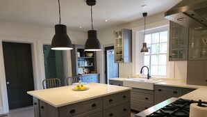 Cocina moderna con una isla central, armarios oscuros e iluminación colgante.