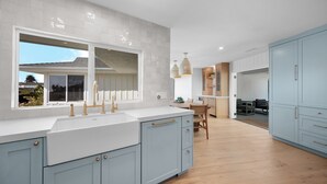 A modern kitchen with light blue cabinets, a white countertop, and a large window. - Oceanview Bliss - San Clemente (San Clemente)