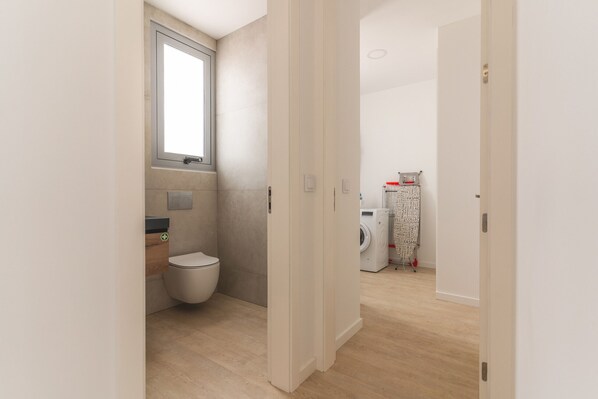A modern bathroom with a toilet, sink, and window. - Villa Alegria by Atlantic Holiday (Calheta)