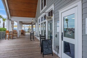 A café with outdoor seating, a wooden deck, and a sign indicating it's open.