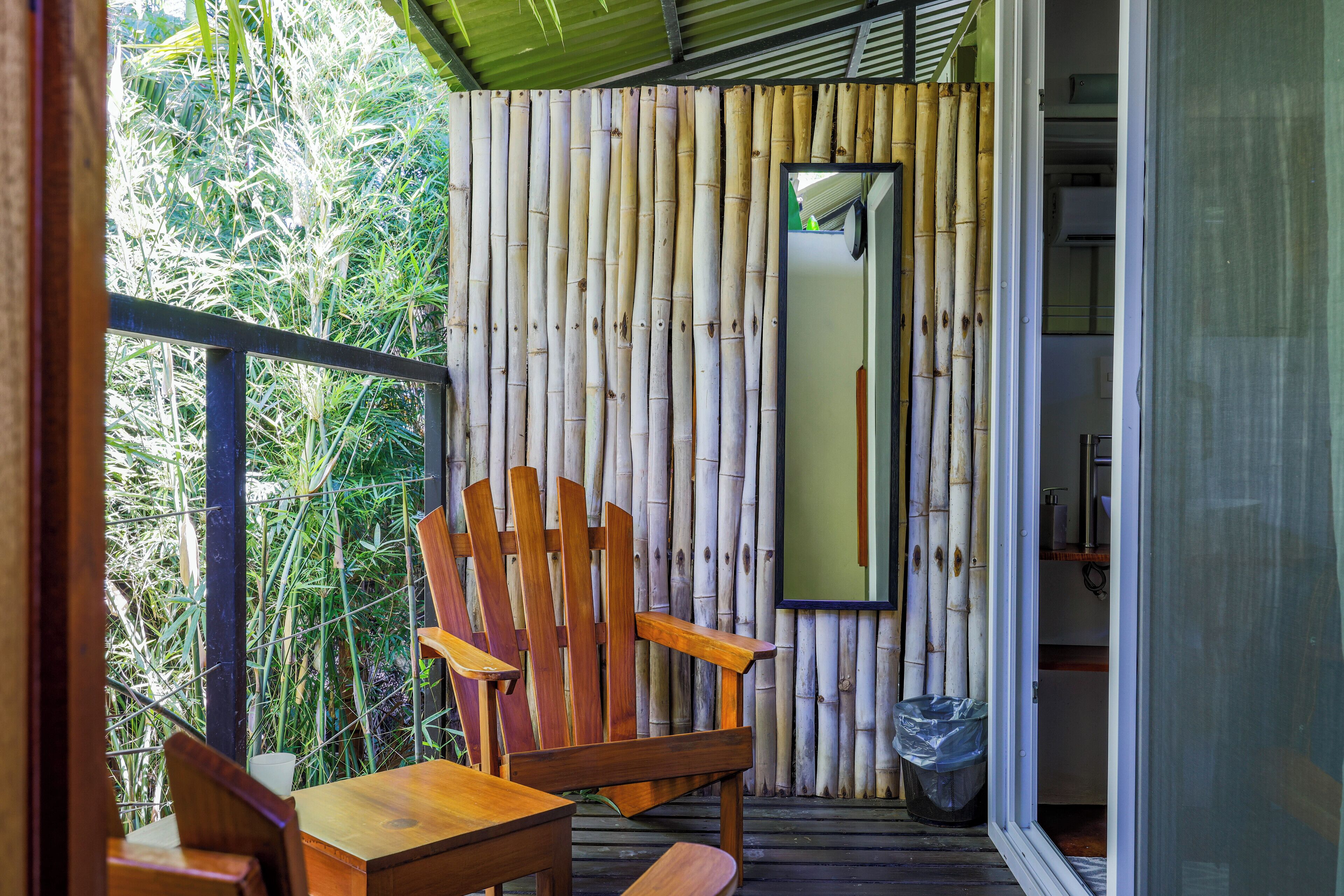 A balcony with a wooden chair, a small table, and a bamboo wall.