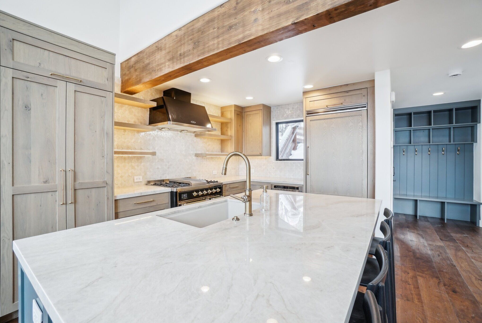 A modern kitchen with a large island, built-in appliances, and wooden beams.