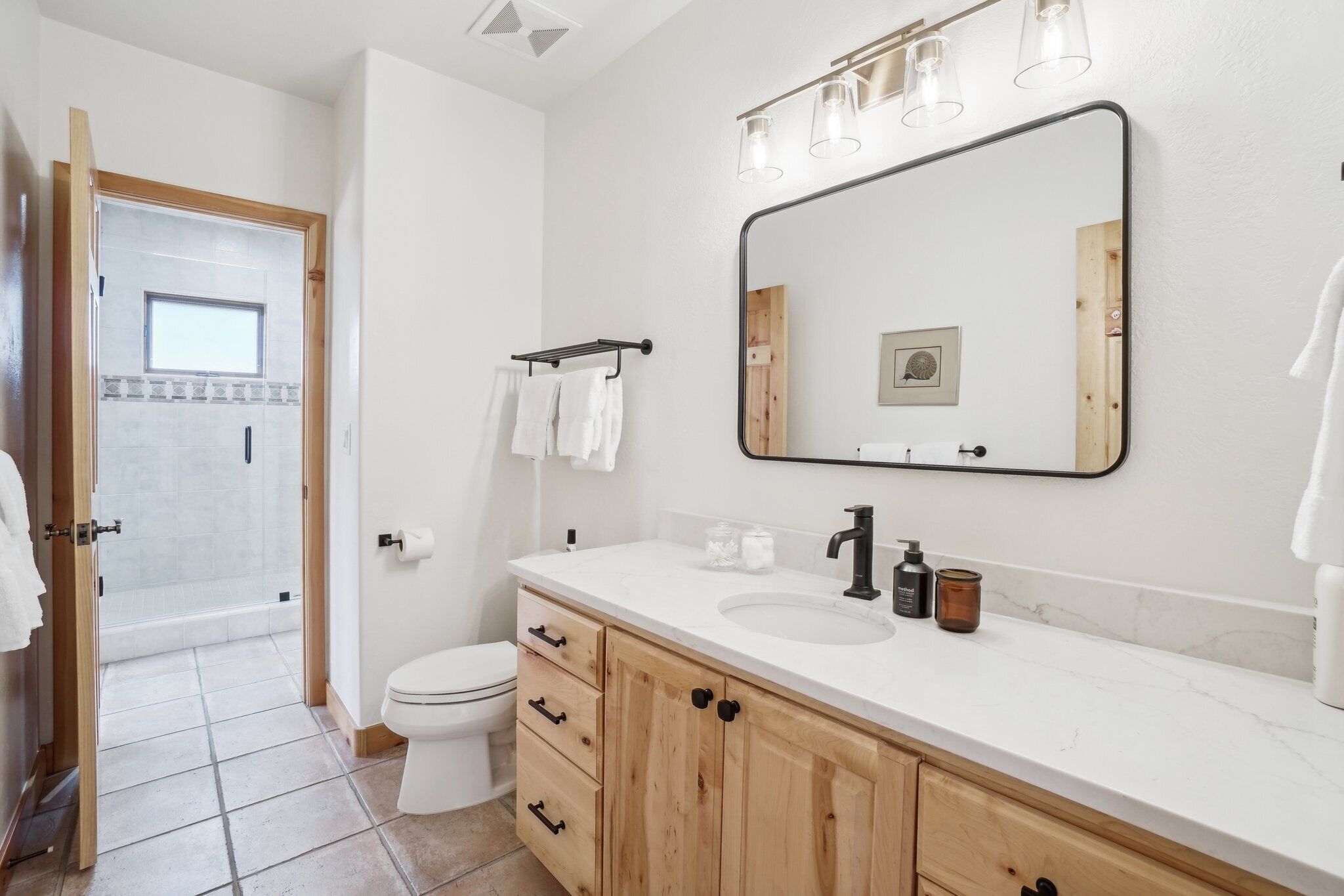 Ett modernt badrum med en vit tvättställ, träskåp, en stor spegel och en duschkabin med glasväggar.