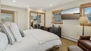 A bedroom with a large bed, a dresser, a mirror, and a painting on the wall.