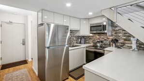 Una cocina moderna con electrodomésticos de acero inoxidable, microondas y salpicadero de azulejos.