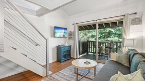 Una sala de estar moderna con una escalera, un mueble azul, una mesa de centro redonda y un sofá.
