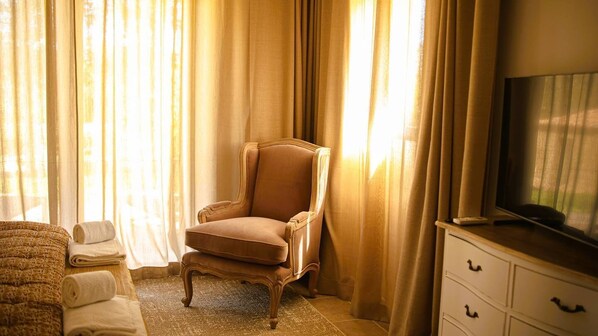 Una habitación con un sofá elegante, un sillón de cuero, un televisor de pantalla plana y un aparador de madera.