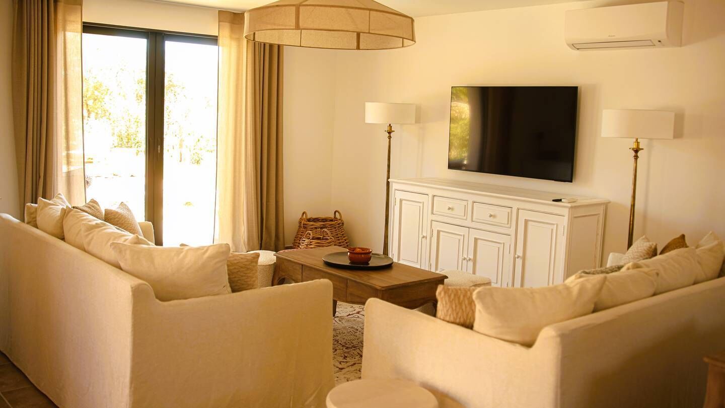 A modern living room with a sofa set, a television, and a dining table.