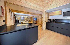 Una cocina moderna con una isla central, armarios oscuros y una pared decorativa de piedra.