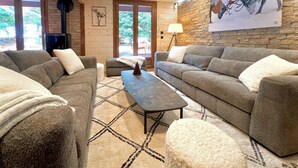 Un salon chaleureux avec un mur en pierre, une cheminée et une grande fenêtre.