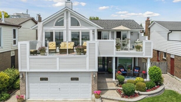 A two-story house with a garage, a covered patio with outdoor furniture, and a well-maintained garden.