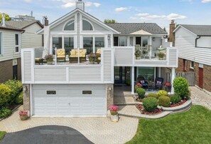 Ein zweistöckiges Haus mit Garage, überdachter Terrasse und Garten.