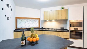 Une cuisine moderne avec des meubles en bois, un plan de travail noir, une plaque de cuisson encastrée et un four.