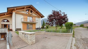 Une maison à deux étages avec un balcon, un mur de soutènement en pierre et une allée pavée.