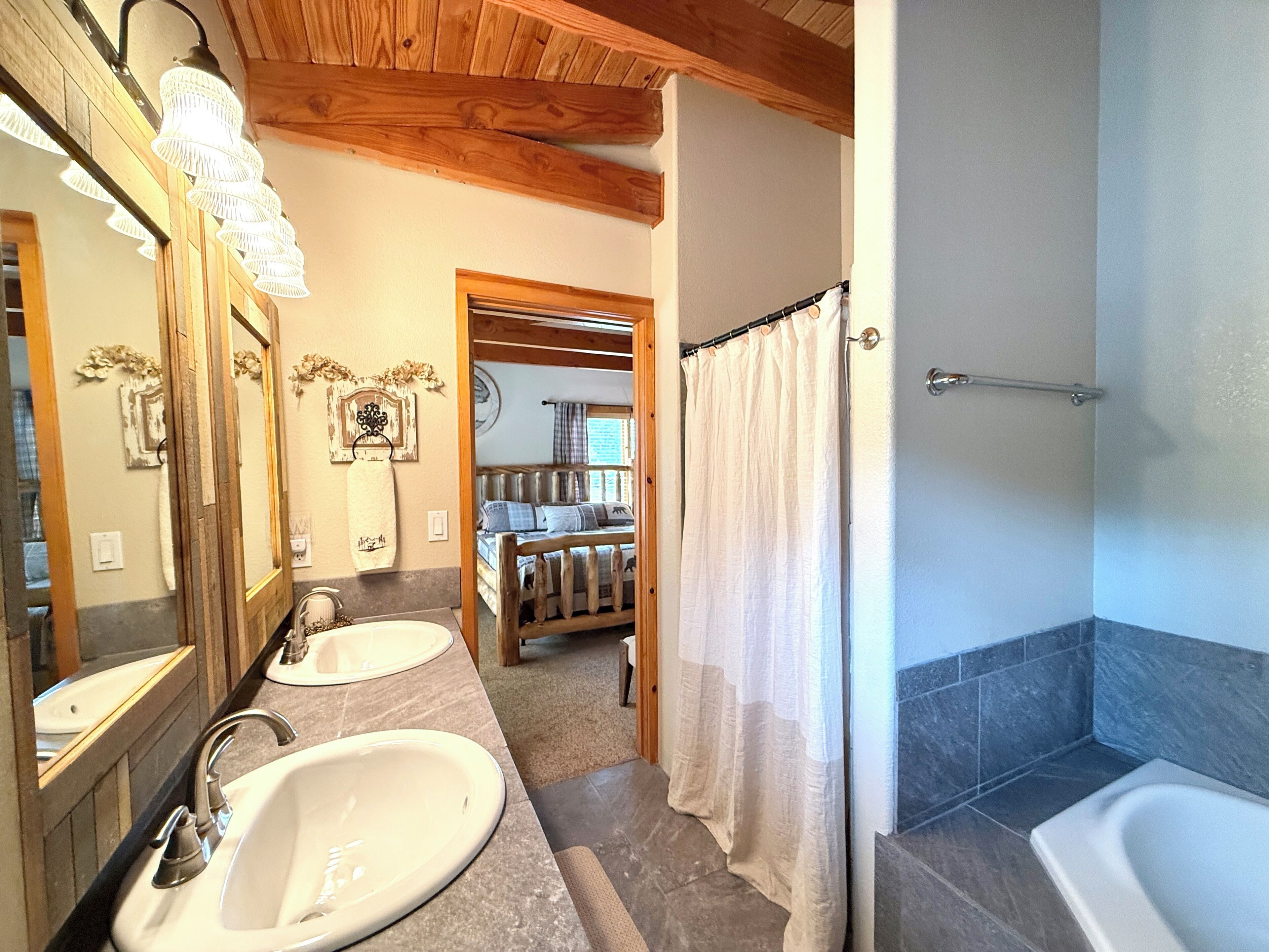 Ein Badezimmer mit zwei Waschbecken, einer Dusche und einer Holzbalkendecke.