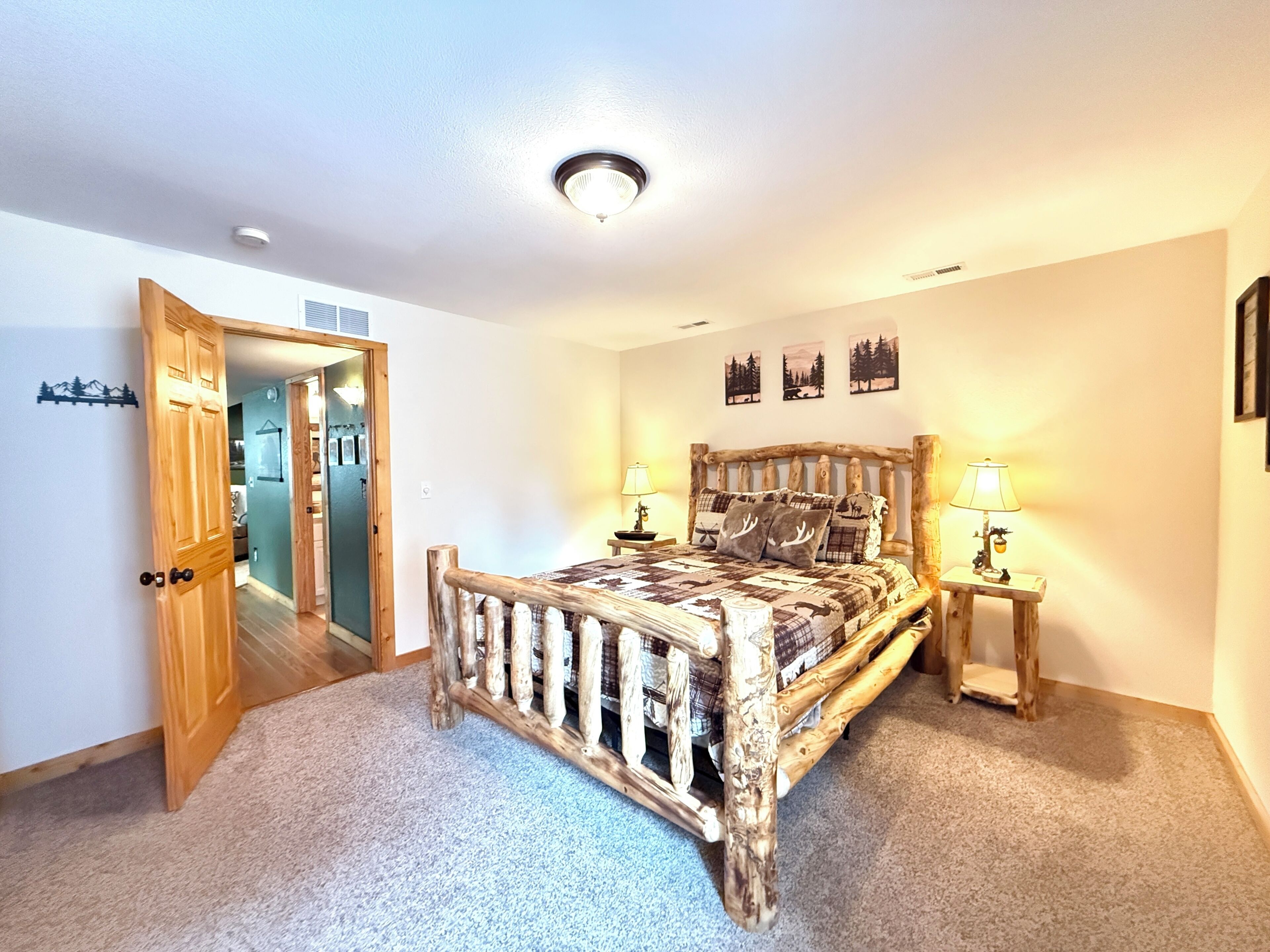 Un dormitorio con cabecera de cama de madera, dos lámparas de noche y una puerta que da a otra habitación.