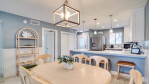 A modern kitchen with a central island, pendant lighting, and a dining area with a round table and chairs. - Run Away Bay 181 by SeaBreeze Vacation (Bradenton Beach)