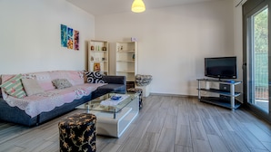 Ein Wohnzimmer mit Sofa, Couchtisch, TV-Schrank und Regalen.