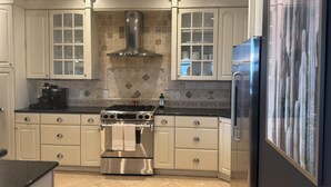 A modern kitchen with white cabinetry, a stainless steel range, and a built-in oven.
