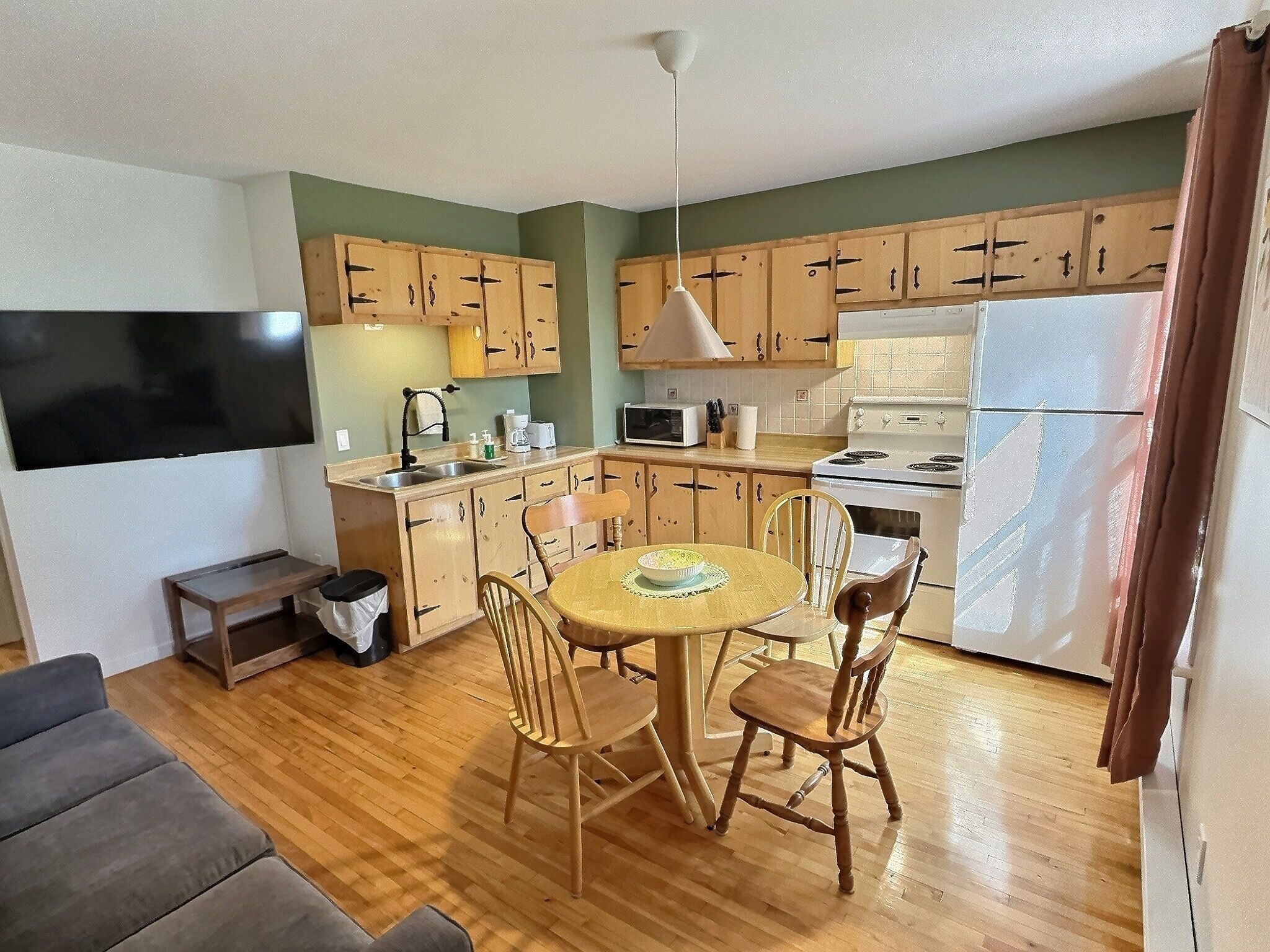 Una cocina compacta con armarios de madera, microondas, estufa y una mesa de comedor con sillas.