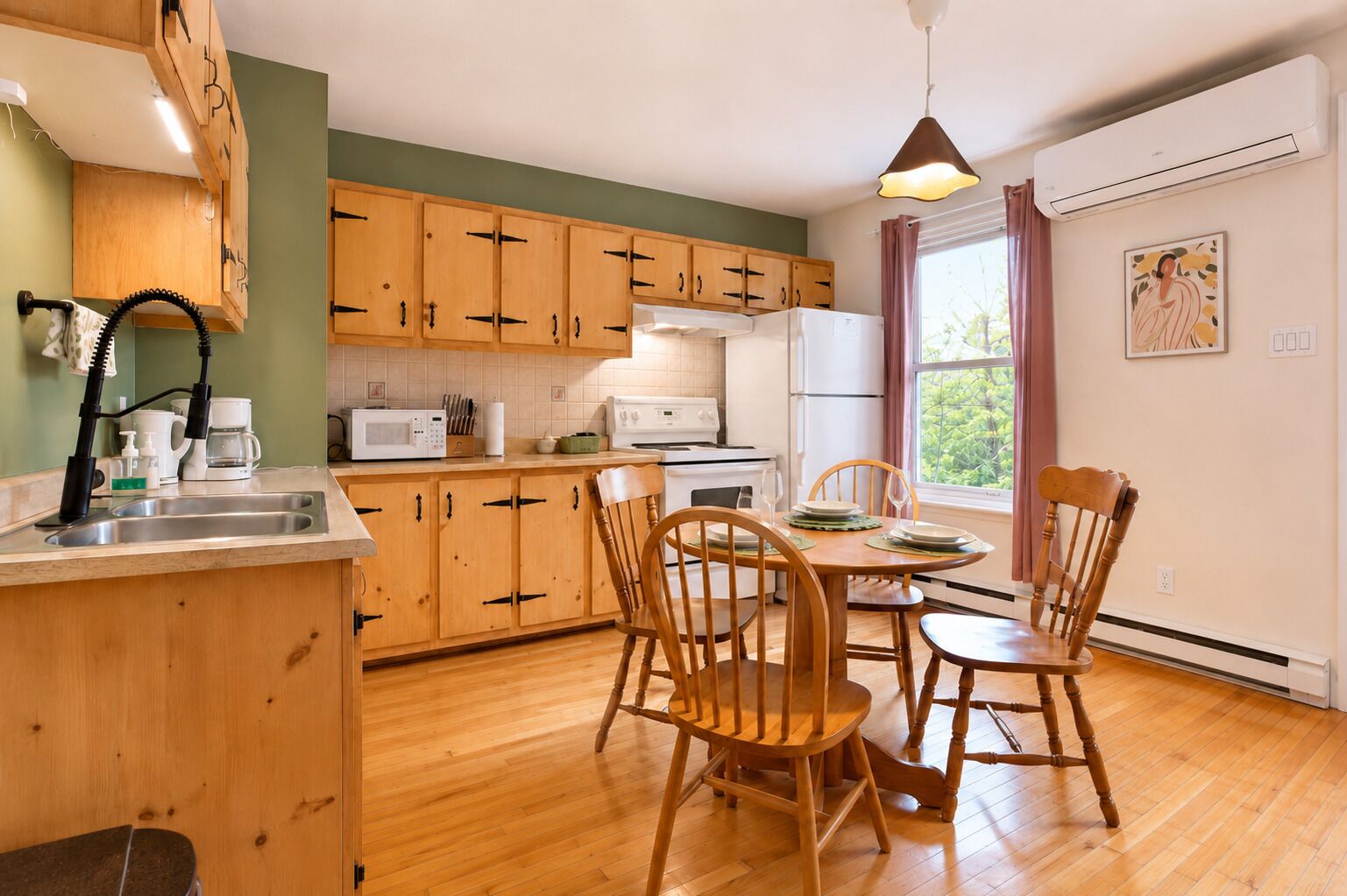 Une cuisine avec des meubles en bois, une table à manger avec des chaises, un four à micro-ondes, un réfrigérateur et une fenêtre avec des rideaux.