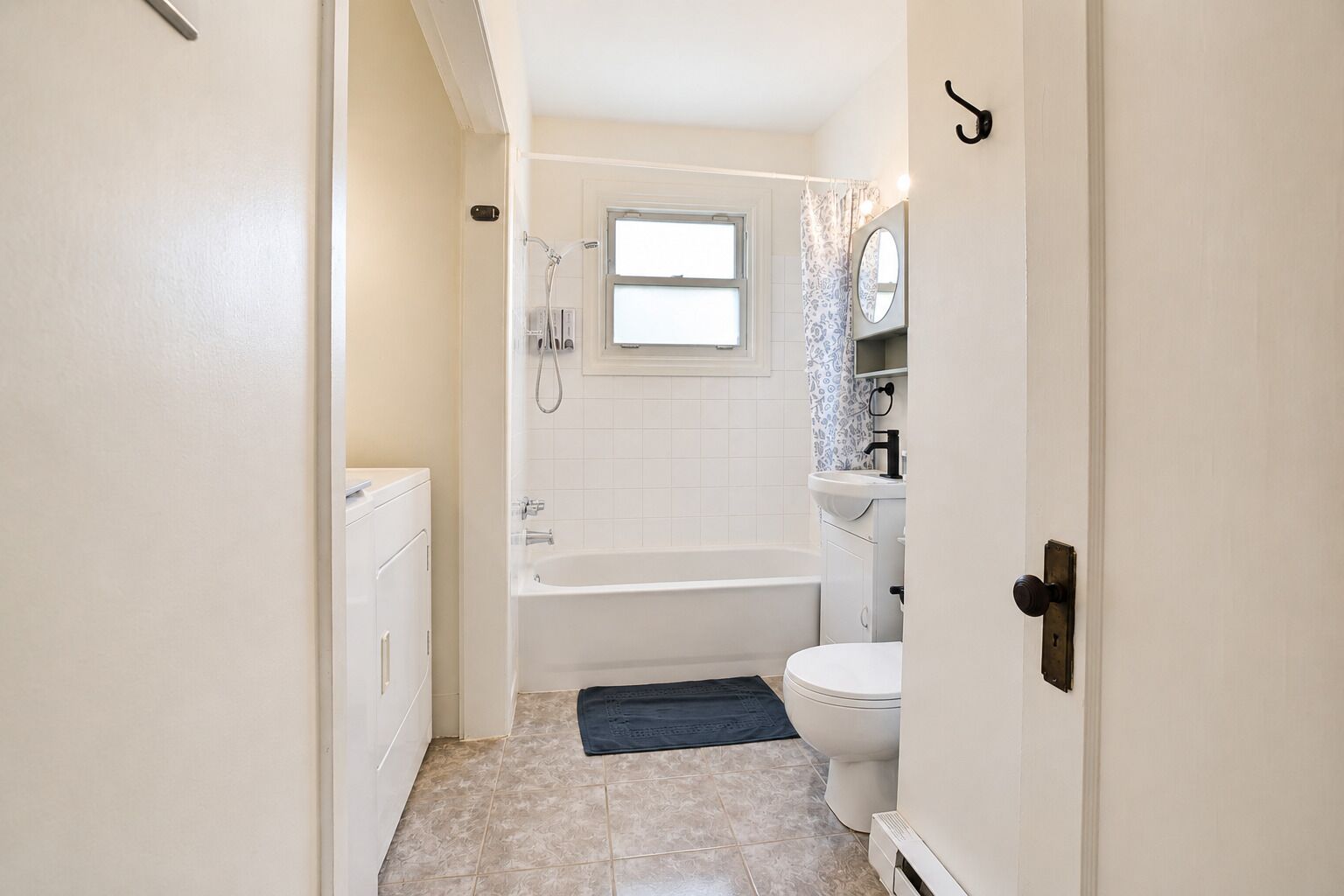 Ein Badezimmer mit Badewanne, Toilette und einem Fenster über dem Waschbecken.