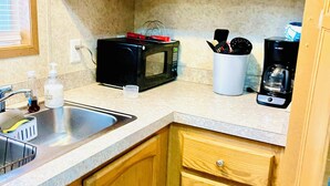 Une cuisine avec des meubles en bois, un four à micro-ondes, une machine à café et un évier.