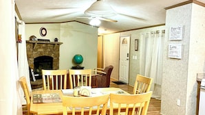 Un coin repas avec une table et des chaises en bois, un ventilateur de plafond et une cheminée.