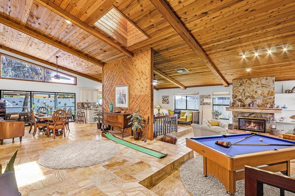 A spacious living room with a pool table, wooden ceiling, and large windows overlooking a scenic view. - Luxury meets Leisure - Viscaya Paradise - Roelens (Cape Coral)