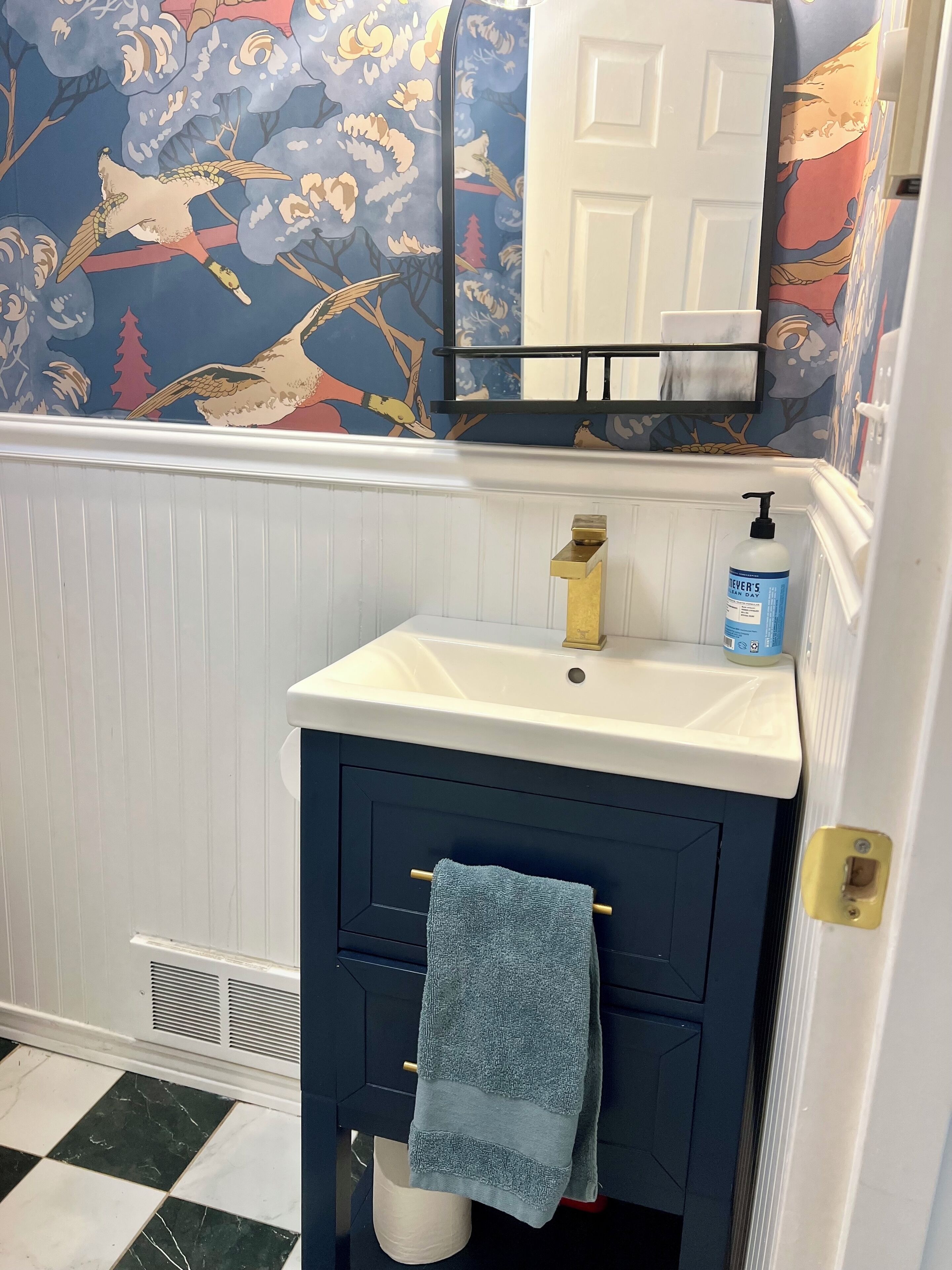 Une salle de bain avec un lavabo blanc, une serviette bleue et un miroir au-dessus.