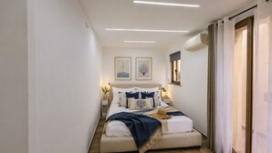 A narrow, well-lit bedroom with a bed, bedside tables, and artwork on the walls. - Bedda Sicily (Riposto)