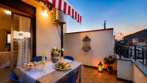 An outdoor dining area with a table set for a meal, a decorative vase, and a lantern. - Bedda Sicily (Riposto)