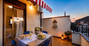 An outdoor dining area with a table set for a meal, a decorative vase, and a lantern.